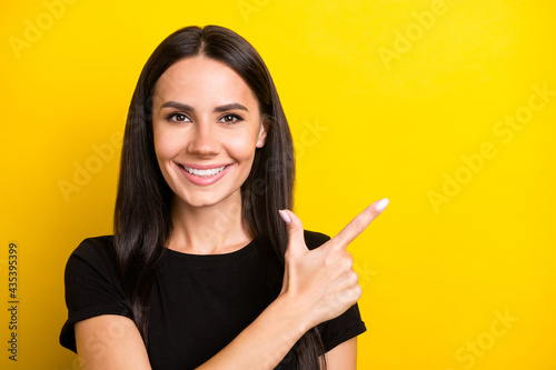 Photo of cheerful promoter lady direct finger empty space wear black t-shirt isolated yellow color background