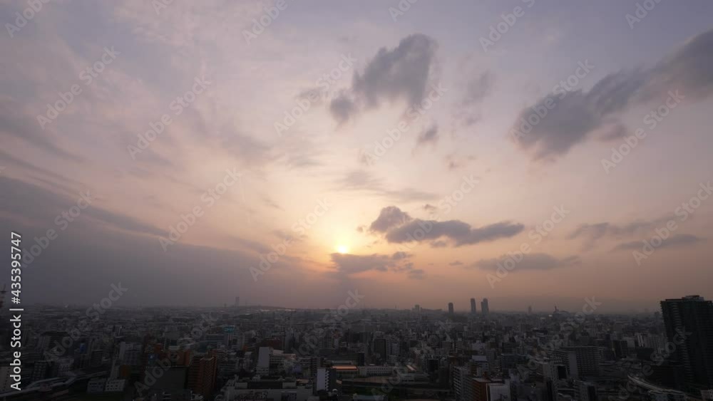 Stretched clouds over horizon line, and sun shine through. Evening panorama, aerial cityscape of Osaka, camera turn right. Dark buildings of Japanese metropolis Stretched clouds over horizon line, and sun shine through. Evening panorama, aerial cityscape of Osaka, camera turn right. Dark buildings of Japanese metropolis