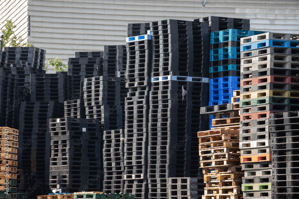 Obraz premium industry plastic and wooden pallets in factory yard background. shipping plastic pallet stacked at factory warehouse. Cargo and shipping concept.