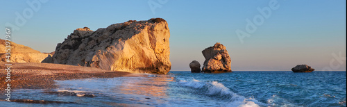 Aphrodite rock Cyprus in soft evening light, curvy waves in the foreground touristic attraction of so called love rock photo