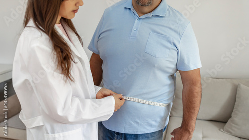 Schilderij op canvas Cropped shot of a female doctor taking obese patient's body fat measurements