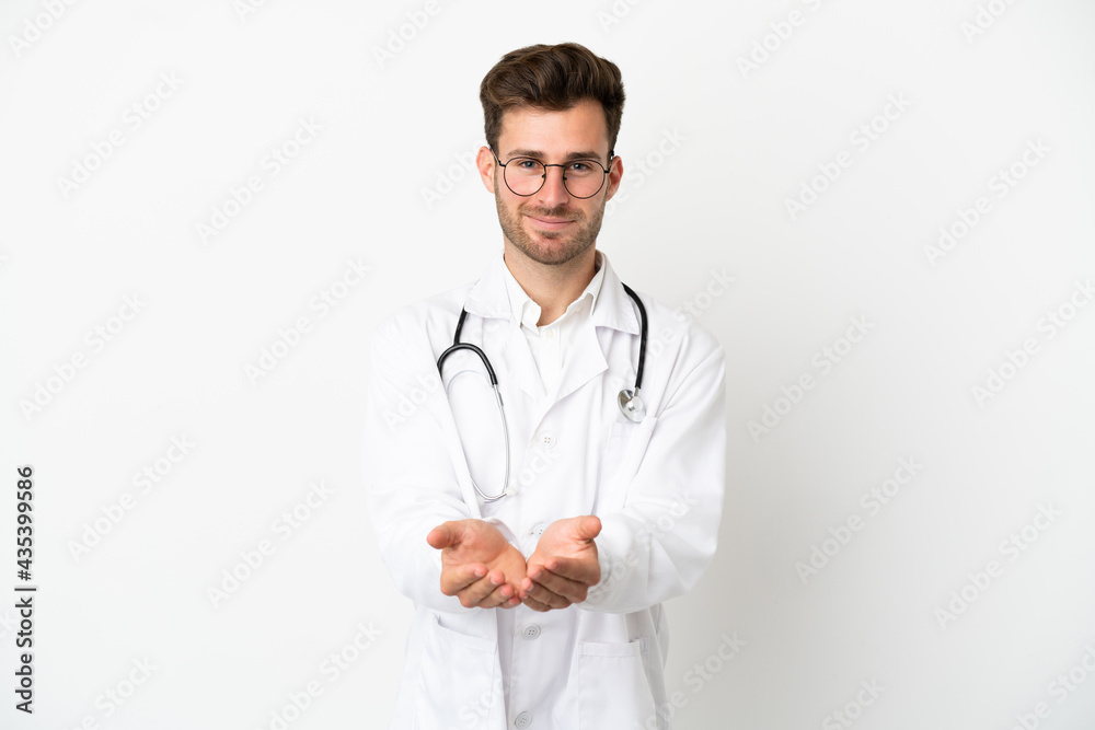 Young doctor caucasian man over isolated on white background wearing a doctor gown and holding something Young doctor caucasian man over isolated on white background wearing a doctor gown and holding something