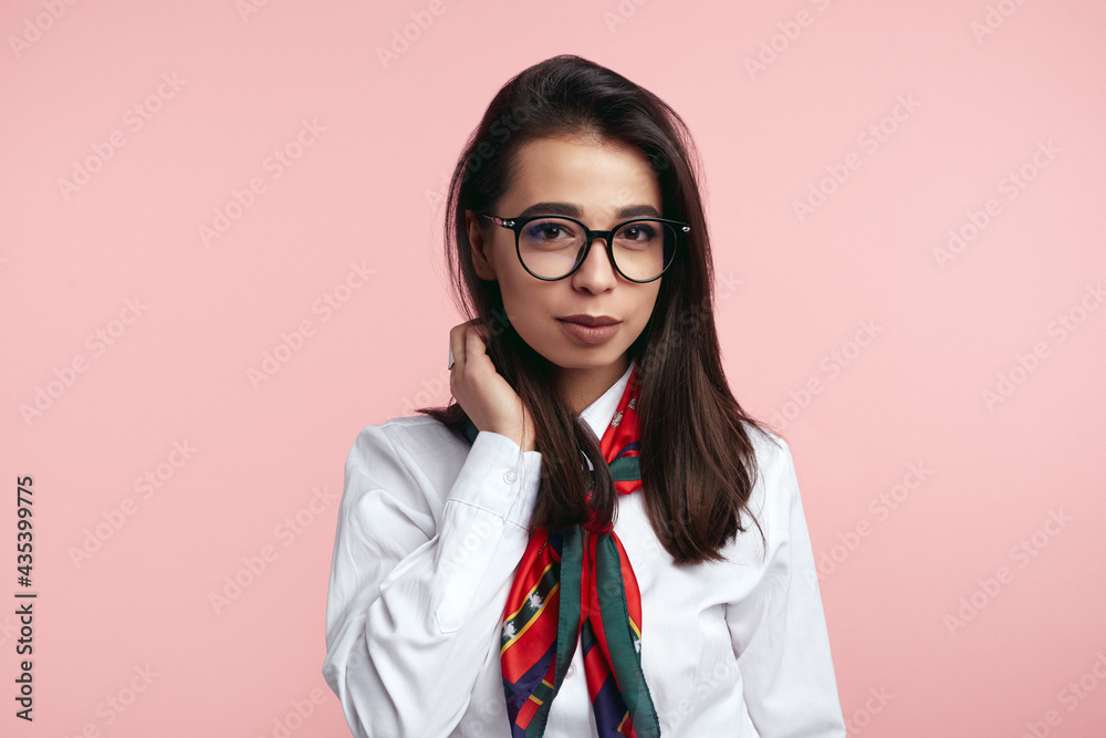 Girl wearing white shirt, eyeglasses and scarf, isolated over pink backdrop