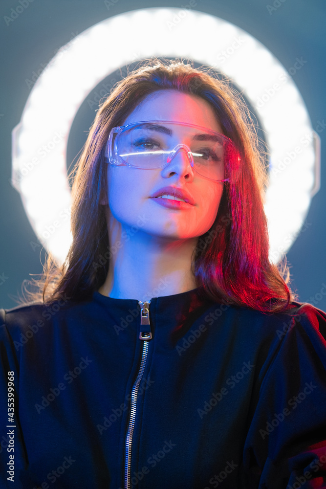 Futuristic portrait. Cyberpunk beauty. Sci-Fi technology. Confident red blue neon light woman face in glasses with white glowing LED round halo.