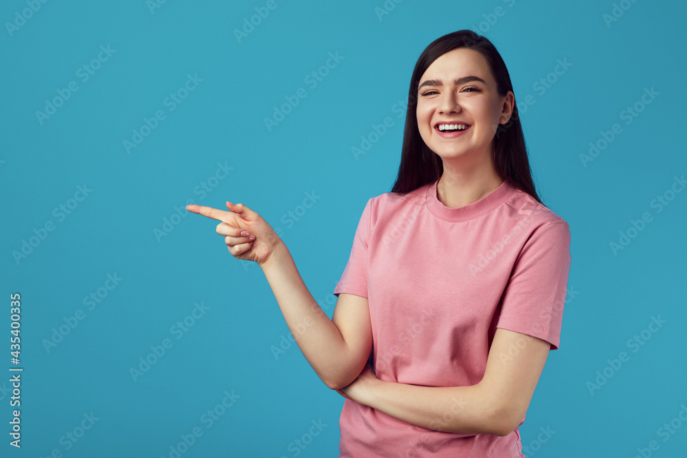 Happy caucasian female model indicates with fore finger at blank copy space Happy caucasian female model indicates with fore finger at blank copy space