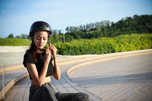 Cute young woman wearing safety healmet before play surskate or outdoor port,Asian mother wears black helmet