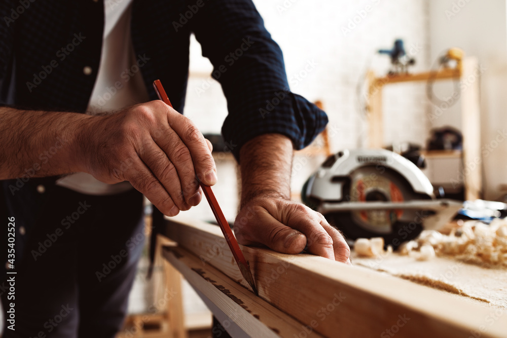 Carpenter makes pencil marks on a wood plank Carpenter makes pencil marks on a wood plank