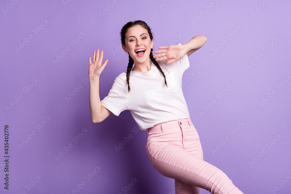Photo of young girl happy positive smile have fun wave hand hello isolated over violet color background Photo of young girl happy positive smile have fun wave hand hello isolated over violet color background