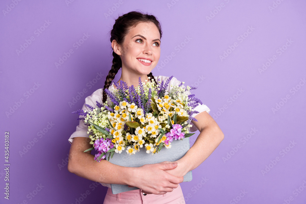 Photo of dreamy happy pretty young woman look empty space good mood hold flowers isolated on violet color background Photo of dreamy happy pretty young woman look empty space good mood hold flowers isolated on violet color background