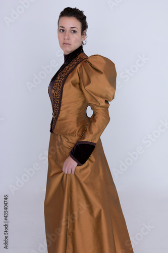 Obraz na plátne A late Victorian woman wearing a bronze and brown silk ensemble with a large hat