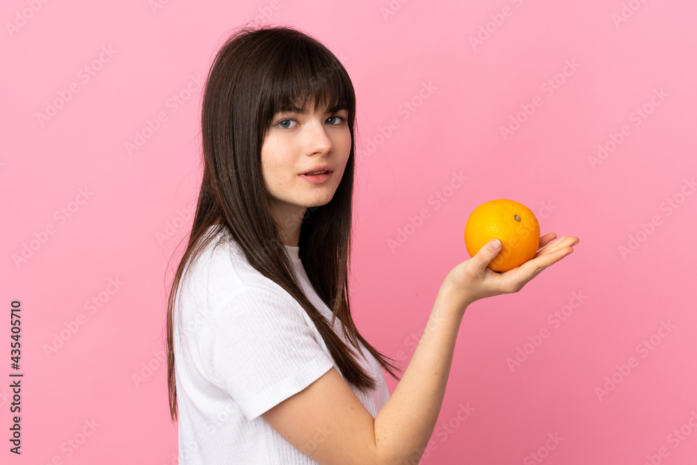Young Ukrainian woman isolated on pink background holding an orange Young Ukrainian woman isolated on pink background holding an orange