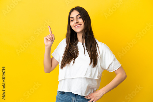Young caucasian woman isolated on yellow background showing and lifting a finger in sign of the best