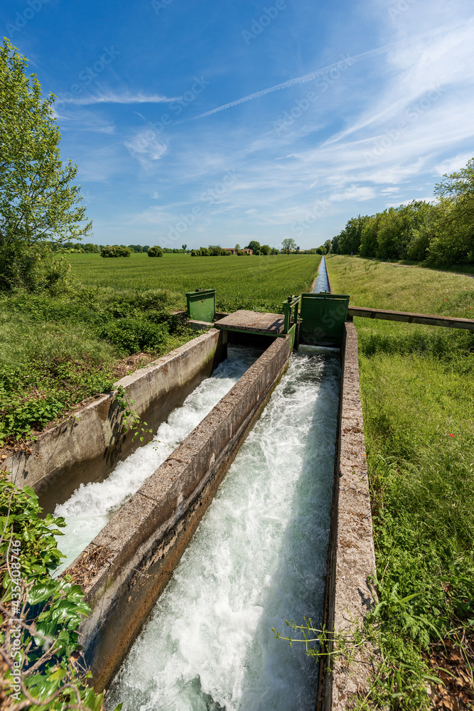 Two small concrete irrigation canals in a rural scene, Padan Plain or Po valley (Pianura Padana, Italian). Mantua province, Italy, southern Europe.