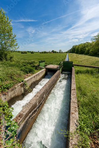 Two small concrete irrigation canals in a rural scene, Padan Plain or Po valley (Pianura Padana, Italian). Mantua province, Italy, southern Europe.