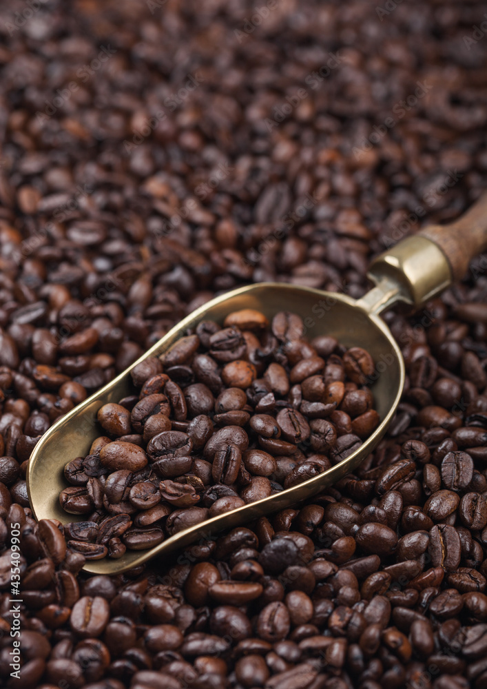 Fototapeta premium Fresh roasted coffee beans in vintage steel scoop on beans background.