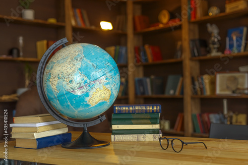 school globe stands on the table next to textbooks on the background of bookshelves, school background for photos