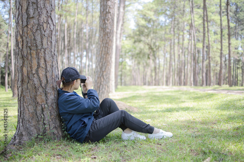 woman taking picture vintage camera while sitting on green grass under the tree in the garden