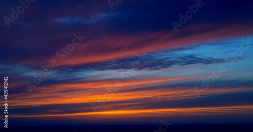 Beautiful orange bright sunset. The clouds are painted in the colors of the sunset and the blue sky