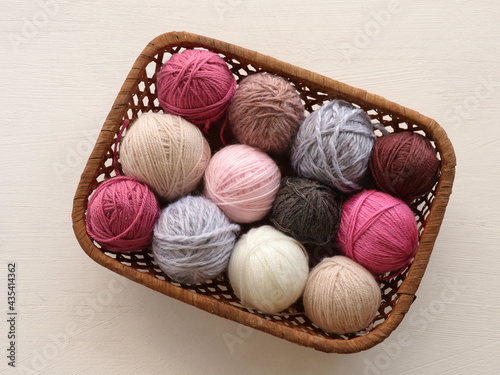 Multicolored knitting yarn balls in basket on white background