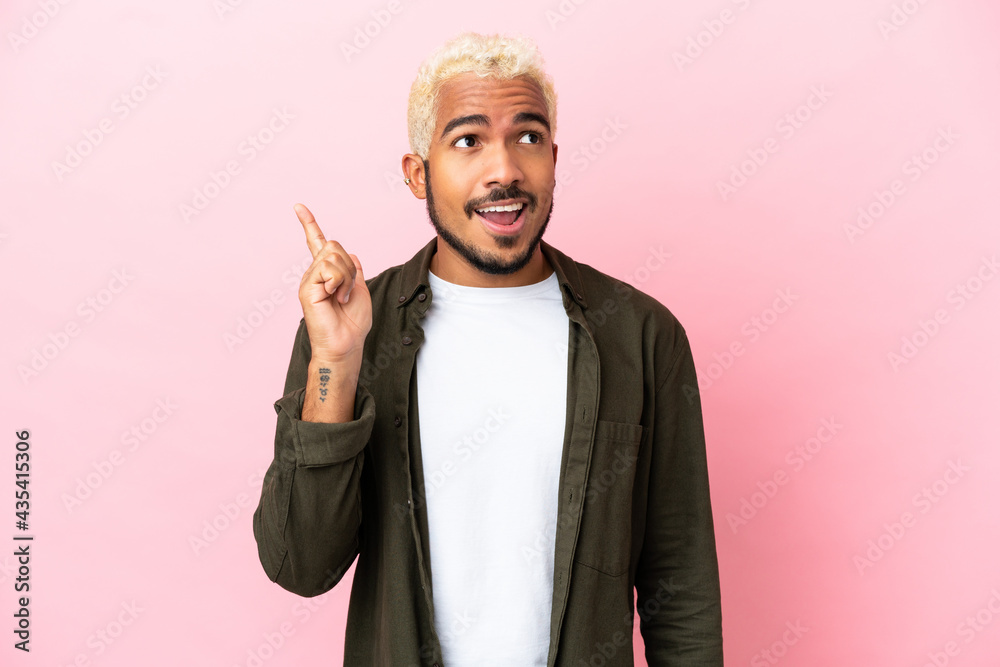 Young Colombian handsome man isolated on pink background intending to realizes the solution while lifting a finger up
