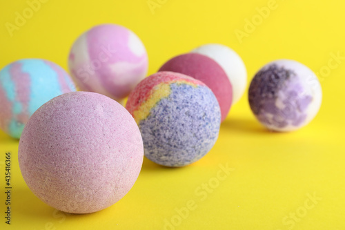 Colorful bath bombs on yellow background, closeup