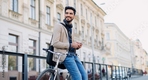 Konstfotografi Young business man commuter with bicycle going to work outdoors in city, using smartphone