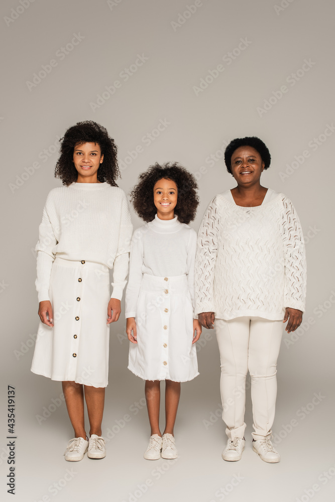 happy african american mother, daughter and grandmother in white clothes on grey background happy african american mother, daughter and grandmother in white clothes on grey background