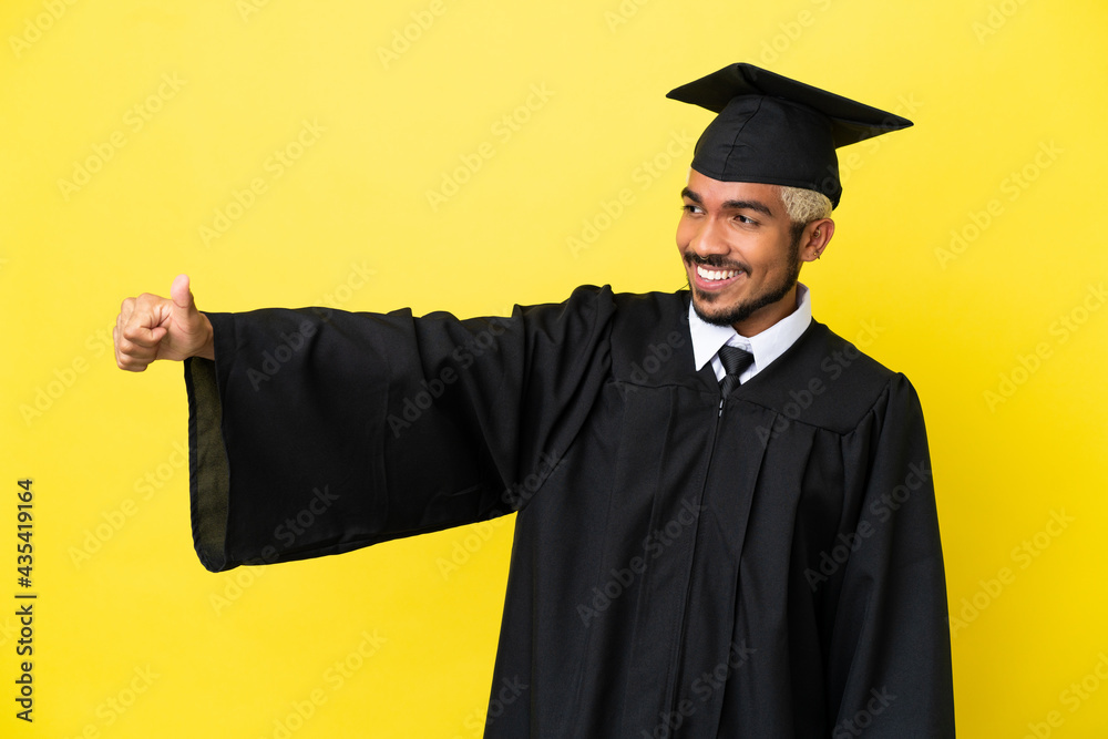 Young university graduate Colombian man isolated on yellow background giving a thumbs up gesture Young university graduate Colombian man isolated on yellow background giving a thumbs up gesture