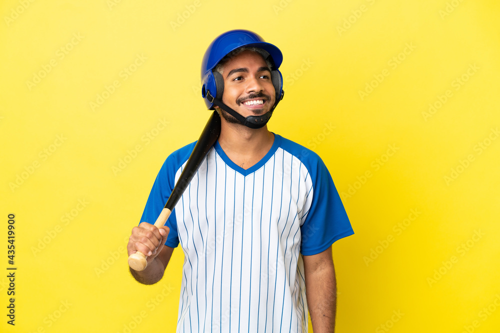 Young Colombian latin man playing baseball isolated on yellow background thinking an idea while looking up Young Colombian latin man playing baseball isolated on yellow background thinking an idea while looking up
