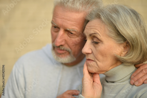 Sad thoughtful senior couple in park