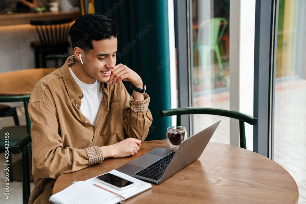 Young hispanic man student sitting at the cafe table indoors Young hispanic man student sitting at the cafe table indoors