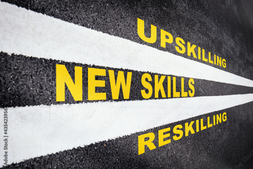New skills development concept and changing skill demand idea. New skills, reskilling and upskilling written on asphalt road with white marking line - obrazy, fototapety, plakaty 
