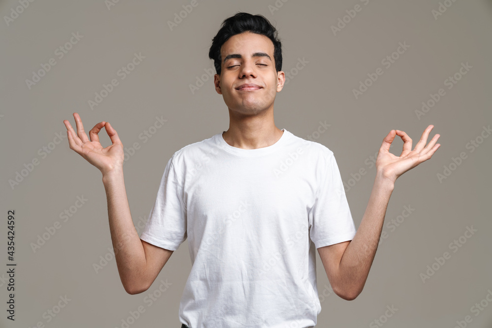 Smiling hispanic man in t-shirt meditating and gesturing Smiling hispanic man in t-shirt meditating and gesturing