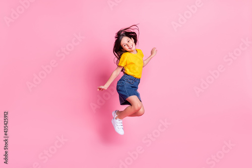 Full length body size view of attractive cheerful cute girl jumping having fun good mood isolated over pink pastel color background