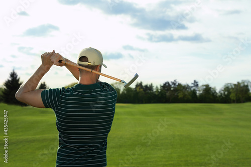 Man playing golf on green course, back view. Space for text