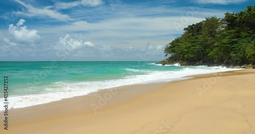 Beach with waves constantly hit the shore. Turquoise water and white bubbles cover the smooth beach. Cloud sky with sunny of holiday in tourism season Phuket, Thailand. Those tourists like to travel.
