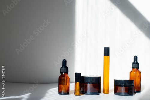 Cosmetic jars with oils on a white background . Light and shadows. Minimalism. Copy space. Cosmetology. Skin care. Cosmetic bottles.