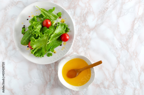 Fotografie Top view of healthy salad wit tomatoes,lettuce and spinach, melted butter on the kitchen table
