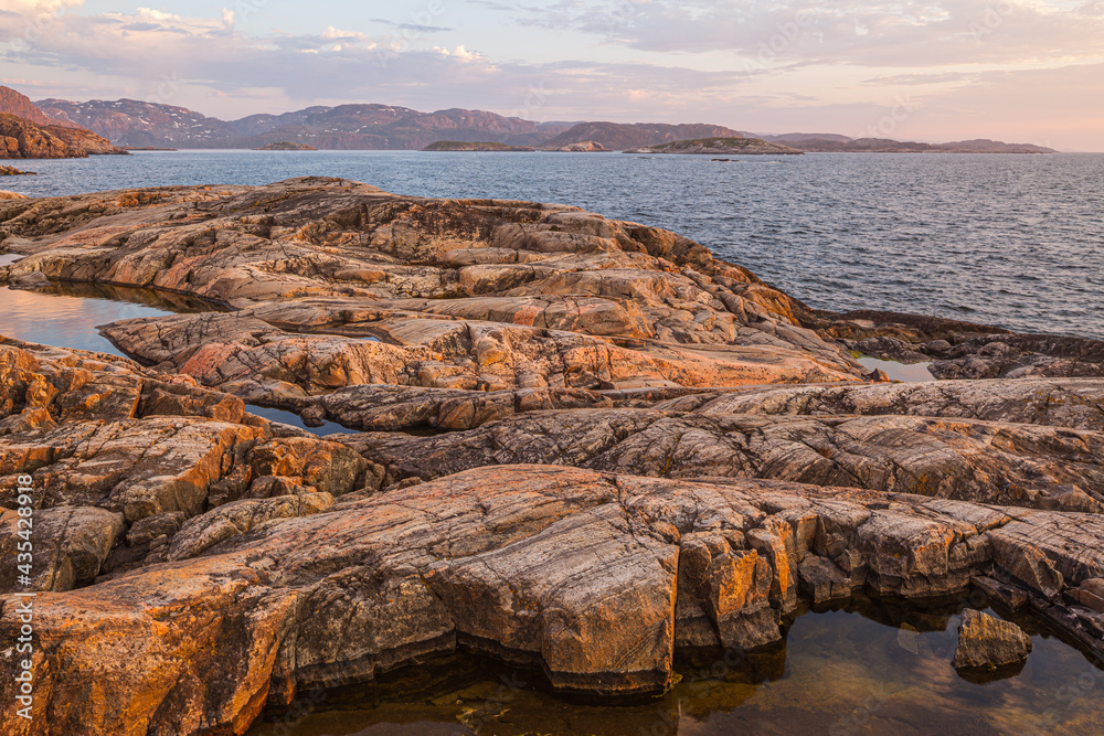 Landscape with smooth-cut bare rocks at the coast of the Barents sea at Grense Jakobselv in midnightsun, Finnmark, Noorwegen