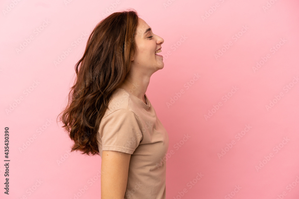 Young caucasian woman isolated on pink background laughing in lateral position Young caucasian woman isolated on pink background laughing in lateral position