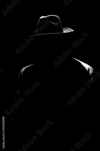 dark mystical silhouette of a man in a hat at night photo