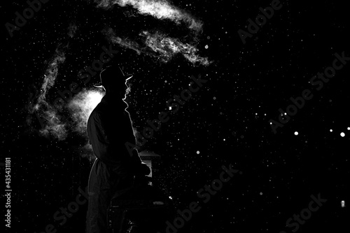 dramatic silhouette of a dangerous man in a hat at night in the rain in the city