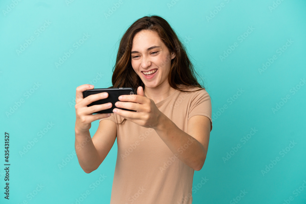 Young caucasian woman isolated on blue background playing with the mobile phone Young caucasian woman isolated on blue background playing with the mobile phone