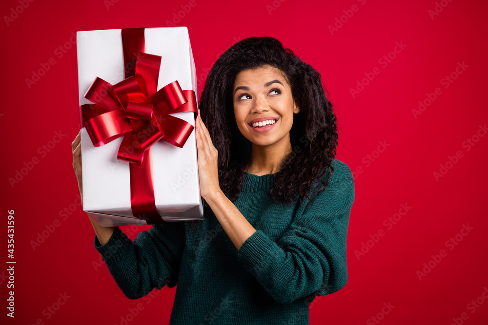 Photo of brunette impressed young lady hold present look empty space wear green sweater isolated on red color background