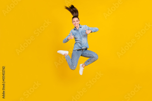 Full length body size photo young pretty girl jumping up showing thumb-up sign isolated bright yellow color background