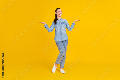 Full length photo of charming pretty lady dressed jeans shirt showing scales arms empty space isolated yellow color background