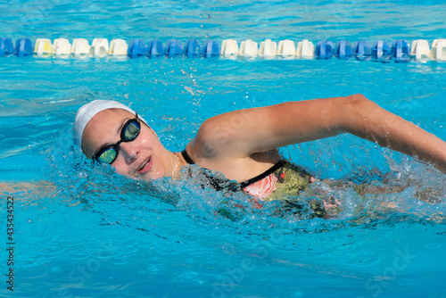 young beautiful woman with swimsuit swimming on a blue water pool