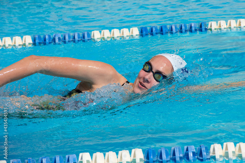 young beautiful woman with swimsuit swimming on a blue water pool