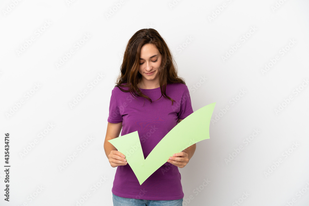Young caucasian woman isolated on white background holding a check icon and looking it Young caucasian woman isolated on white background holding a check icon and looking it