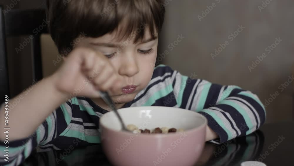 Child Eat Cornflakes with Milk. Little Hungry Boy Eating Breakfast Corn Cereal From Plate Sitting Home at Table in Kitchen. Healthy Nutrition Flakes. Portrait of Kid Eating Eating Muesli for Breakfast Child Eat Cornflakes with Milk. Little Hungry Boy Eating Breakfast Corn Cereal From Plate Sitting Home at Table in Kitchen. Healthy Nutrition Flakes. Portrait of Kid Eating Eating Muesli for Breakfast